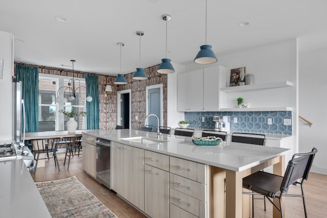 kitchen with decorative light fixtures, sink, a kitchen island with sink, and a breakfast bar area