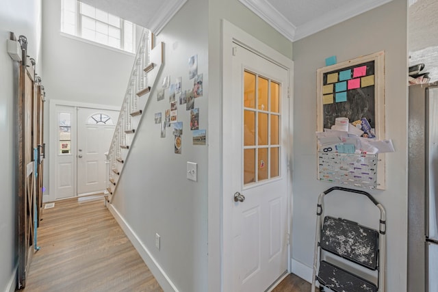 foyer entrance with a barn door, light hardwood / wood-style flooring, and crown molding