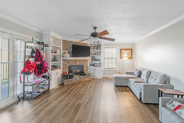 living room featuring ceiling fan, a fireplace, wood-type flooring, and ornamental molding