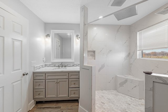 bathroom featuring vanity, wood-type flooring, a textured ceiling, and tiled shower