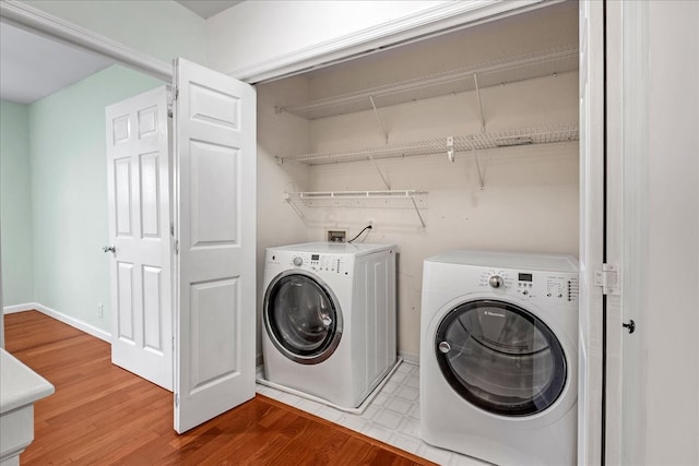 clothes washing area with independent washer and dryer and hardwood / wood-style floors