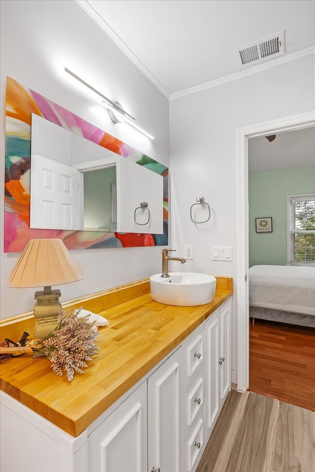 bathroom with hardwood / wood-style floors, vanity, and ornamental molding