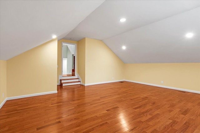 additional living space with hardwood / wood-style floors and lofted ceiling