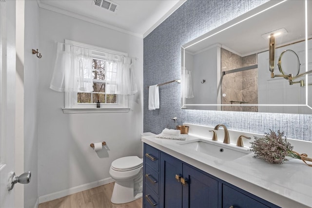 bathroom featuring vanity, wood-type flooring, toilet, ornamental molding, and a shower with shower door