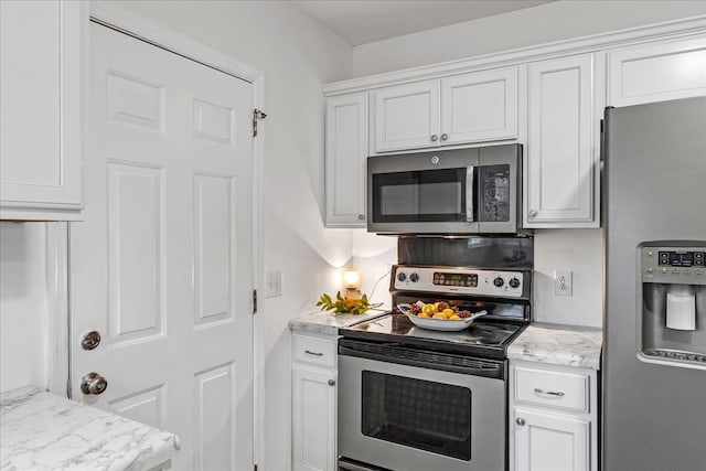 kitchen featuring white cabinets, appliances with stainless steel finishes, and light stone counters