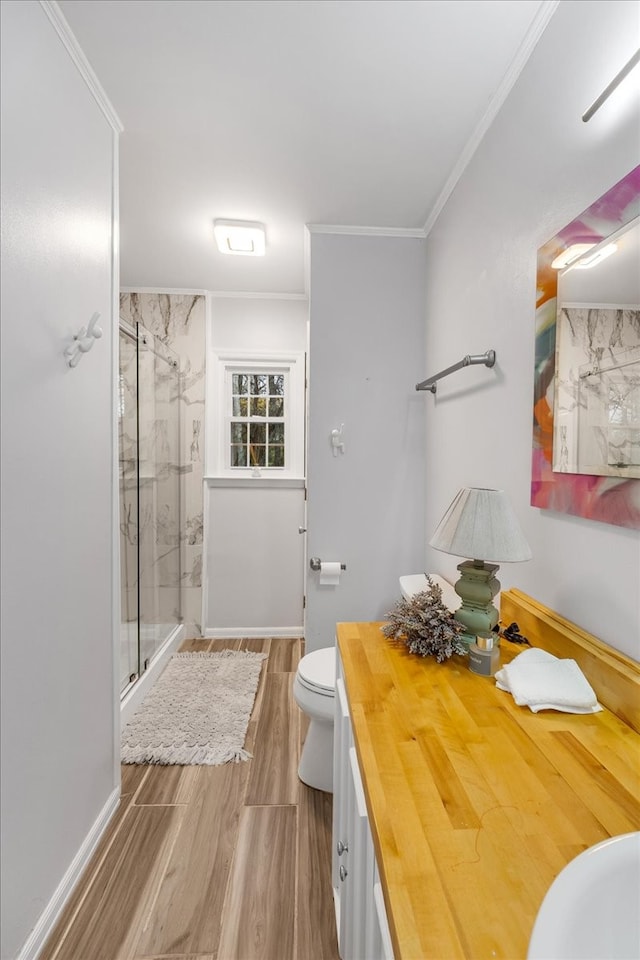 bathroom with crown molding, hardwood / wood-style floors, toilet, vanity, and a shower with shower door