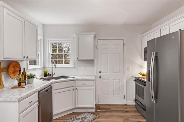 kitchen featuring light hardwood / wood-style floors, sink, white cabinetry, and stainless steel appliances