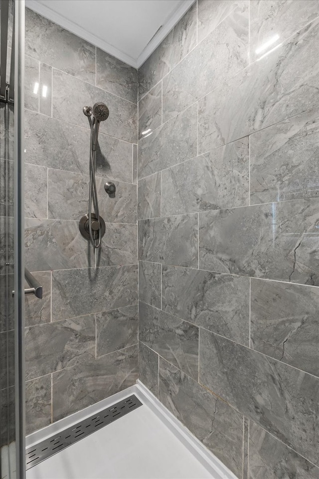 bathroom with crown molding and tiled shower