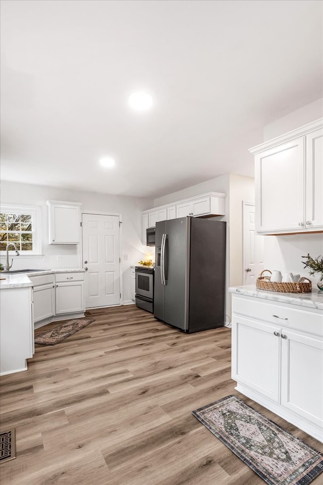 kitchen with white cabinetry, sink, appliances with stainless steel finishes, and light hardwood / wood-style flooring