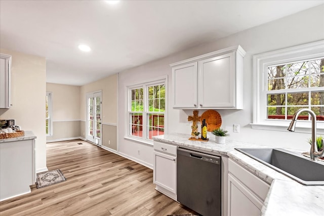 kitchen featuring sink, stainless steel dishwasher, light wood-type flooring, light stone counters, and white cabinetry