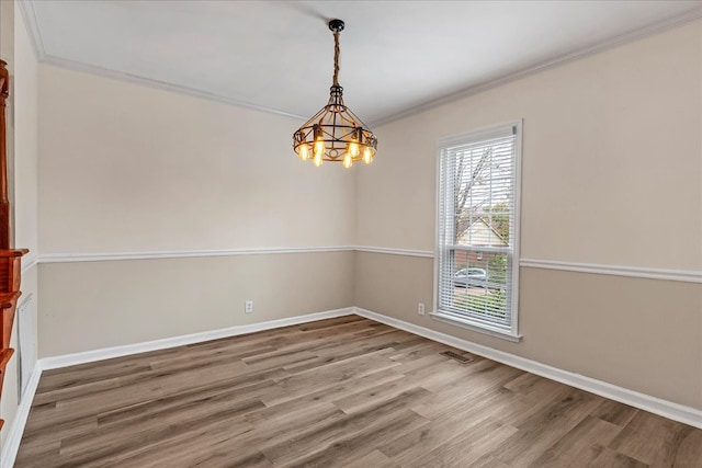 spare room featuring hardwood / wood-style floors, a chandelier, and ornamental molding