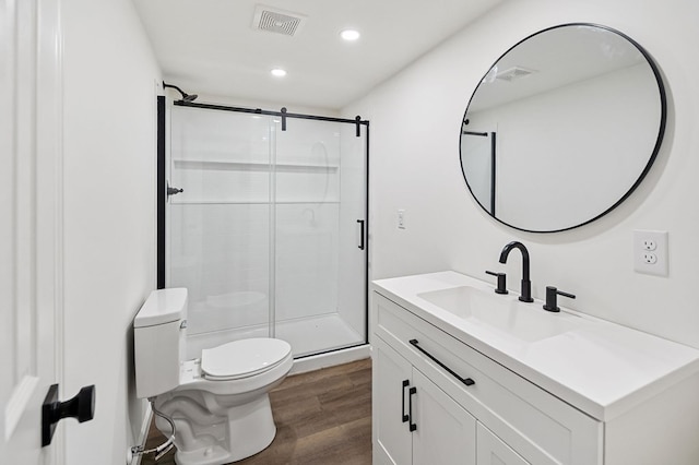 bathroom with an enclosed shower, vanity, toilet, and wood-type flooring