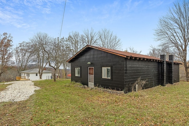 view of side of property with a lawn and an outbuilding