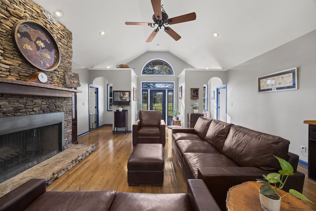 living room with ceiling fan, french doors, a stone fireplace, wood-type flooring, and lofted ceiling