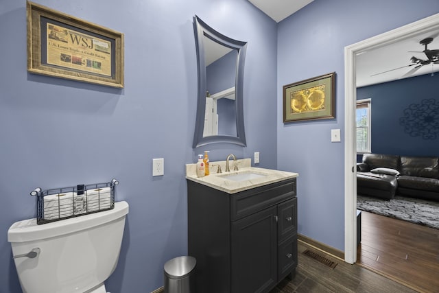 bathroom with wood-type flooring, vanity, toilet, and ceiling fan