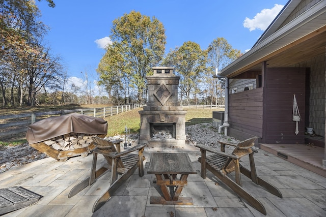 view of patio / terrace featuring an outdoor stone fireplace and a grill