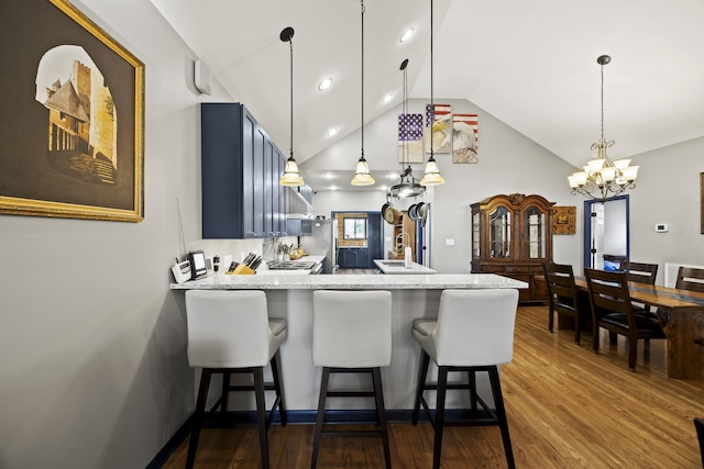 kitchen with kitchen peninsula, vaulted ceiling, light stone countertops, a kitchen bar, and wood-type flooring