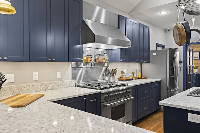 kitchen featuring appliances with stainless steel finishes, light stone counters, wall chimney exhaust hood, dark wood-type flooring, and blue cabinetry