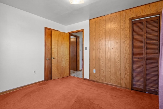 unfurnished bedroom featuring light carpet and wooden walls