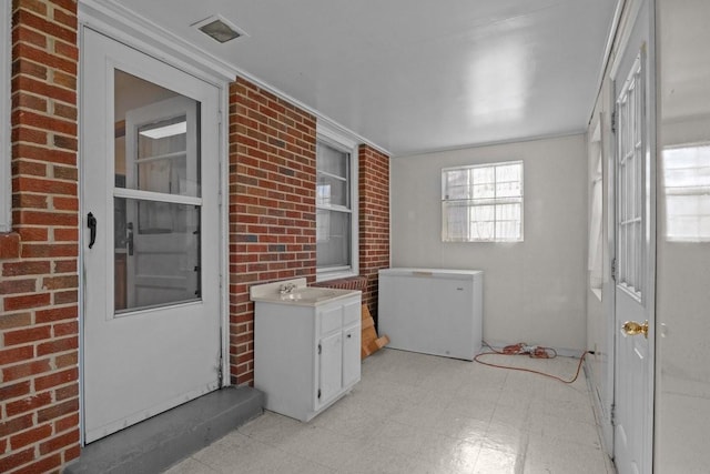 clothes washing area with sink and brick wall