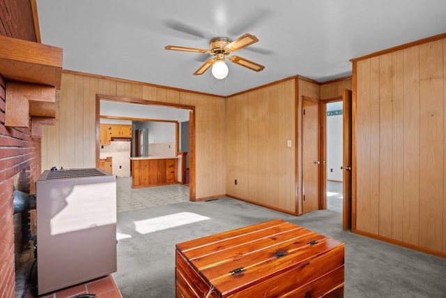 living room with ceiling fan, wooden walls, light carpet, and ornamental molding