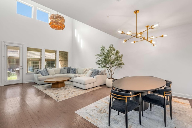 dining area featuring a notable chandelier, a healthy amount of sunlight, a towering ceiling, and dark wood-type flooring