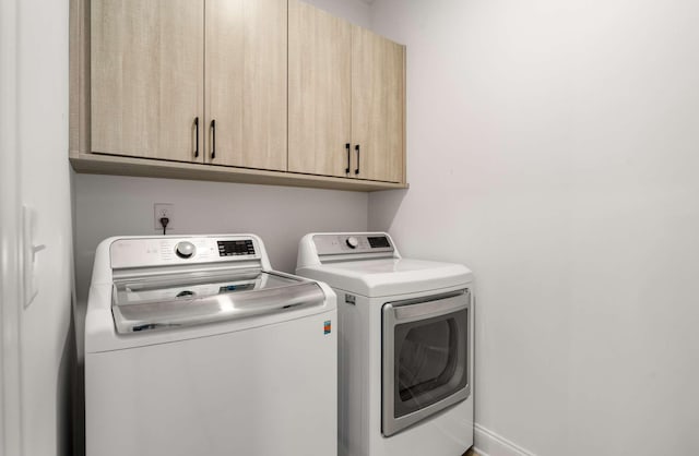 laundry area featuring separate washer and dryer and cabinets