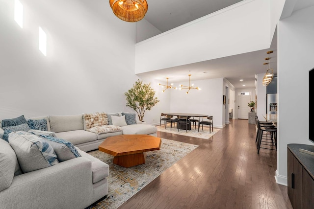 living room featuring dark hardwood / wood-style flooring, a towering ceiling, and a notable chandelier