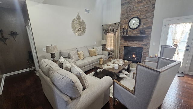 living room with a high ceiling, dark hardwood / wood-style floors, and a stone fireplace