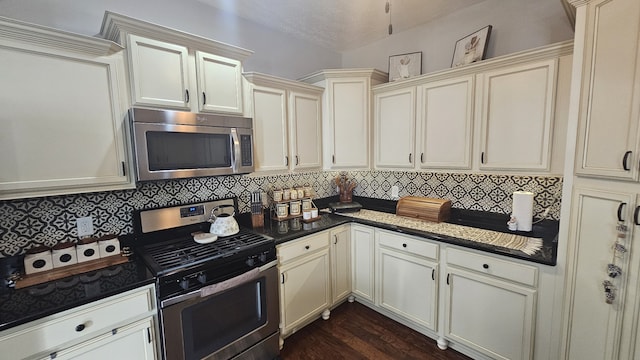 kitchen featuring appliances with stainless steel finishes, tasteful backsplash, dark wood-type flooring, and cream cabinets