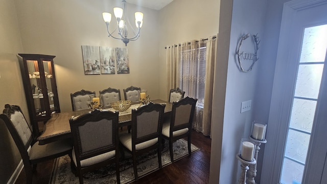 dining area featuring dark wood-type flooring and an inviting chandelier