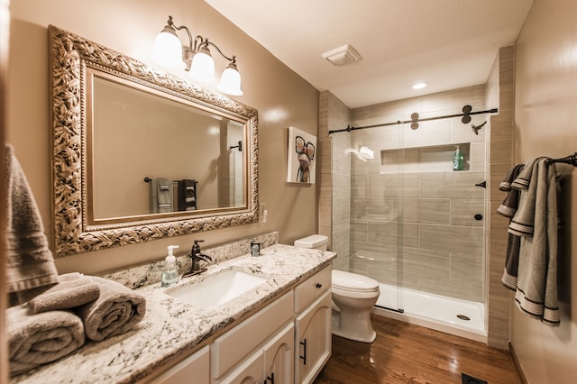 bathroom with hardwood / wood-style floors, vanity, toilet, and a shower with door