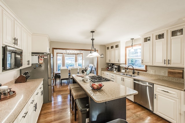 kitchen with decorative light fixtures, stainless steel dishwasher, plenty of natural light, and light hardwood / wood-style floors