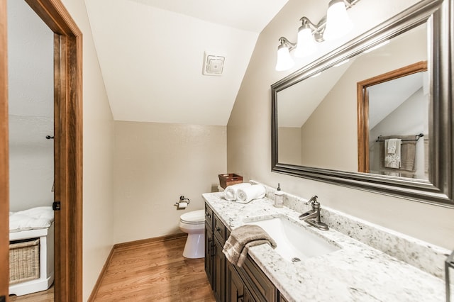 bathroom featuring toilet, vanity, lofted ceiling, and hardwood / wood-style flooring