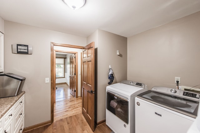 clothes washing area featuring washer and dryer, light hardwood / wood-style flooring, and cabinets