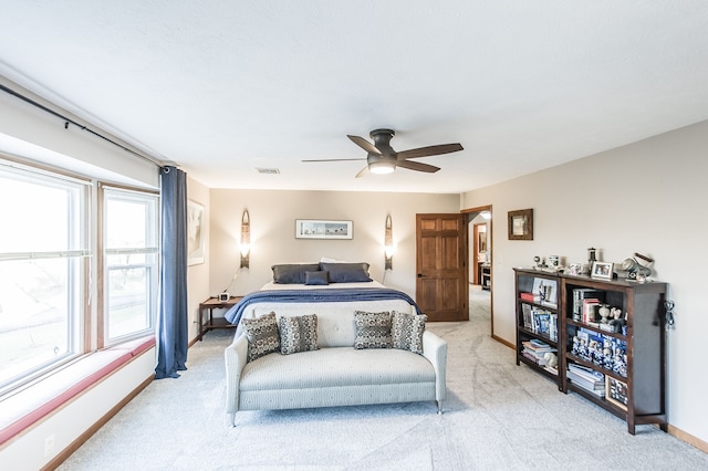 bedroom with light carpet, multiple windows, and ceiling fan