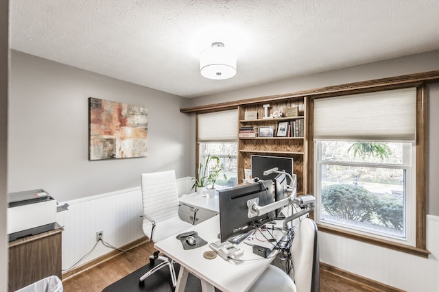 office area with plenty of natural light, wood-type flooring, and a textured ceiling