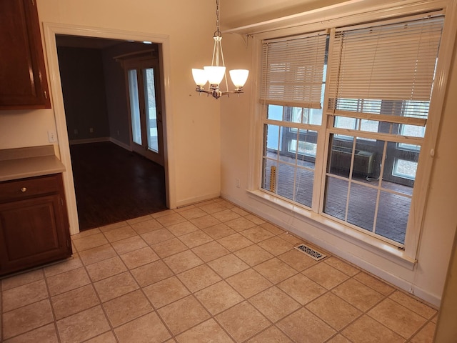 unfurnished dining area with light wood-type flooring and a chandelier