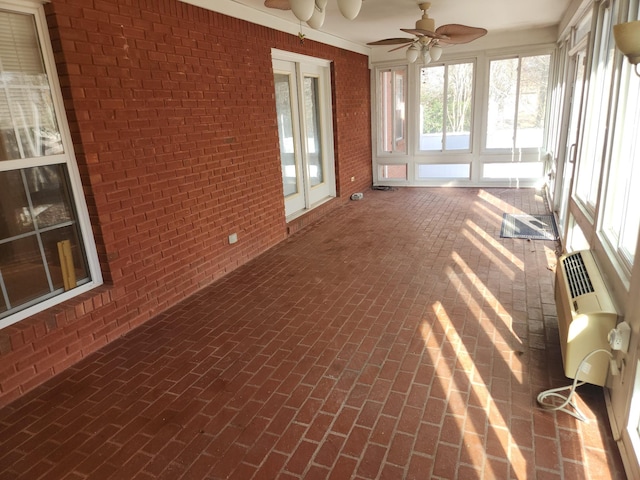 unfurnished sunroom featuring a wall mounted AC and ceiling fan