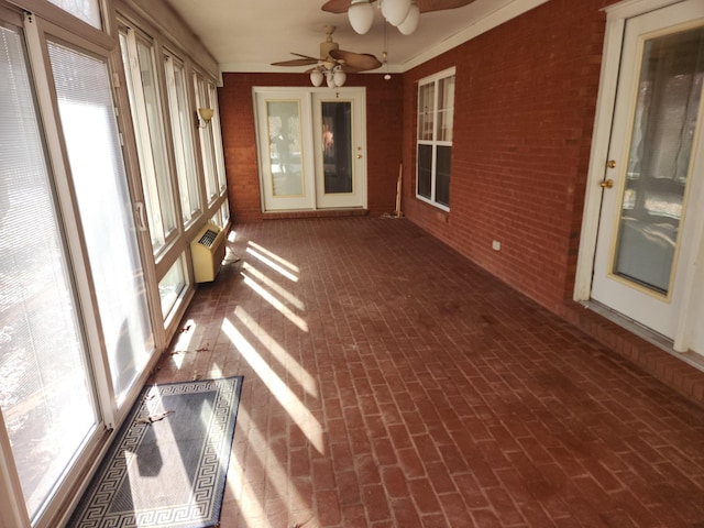 unfurnished sunroom with a wall unit AC and ceiling fan