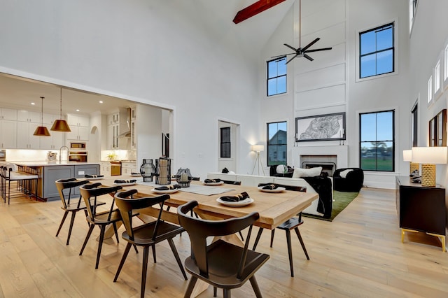 dining area with ceiling fan, sink, a high ceiling, and light hardwood / wood-style flooring