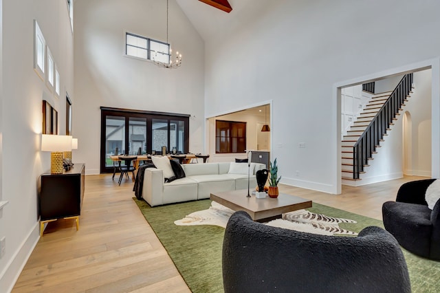 living room with a high ceiling, light hardwood / wood-style flooring, and an inviting chandelier