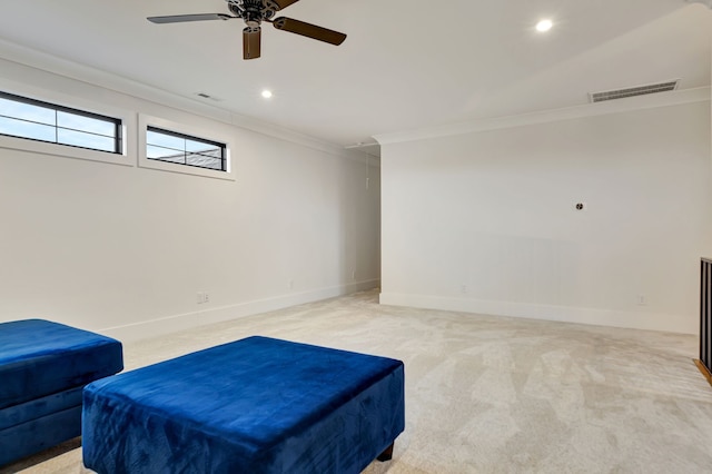 living area with ceiling fan, light colored carpet, and ornamental molding