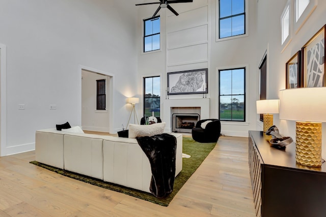 living room featuring ceiling fan, light wood-type flooring, and a high ceiling