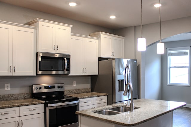 kitchen featuring stainless steel appliances, sink, pendant lighting, a center island with sink, and white cabinetry