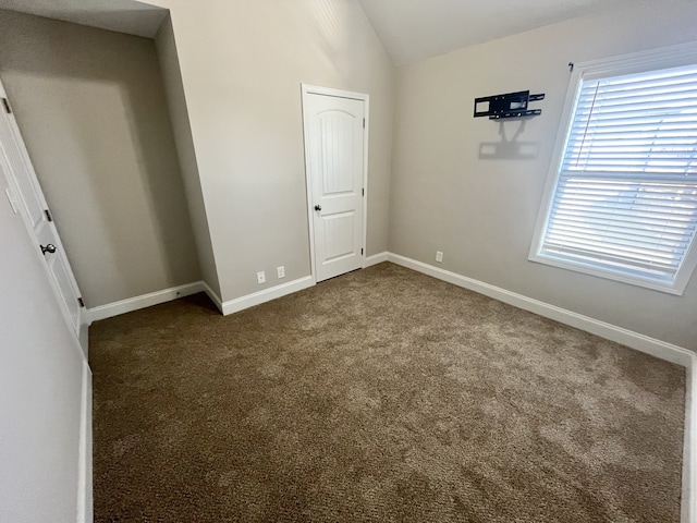 unfurnished bedroom featuring dark colored carpet and vaulted ceiling