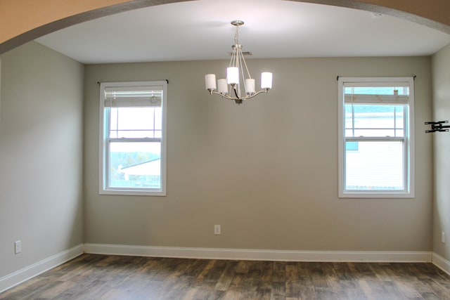 spare room with dark hardwood / wood-style flooring and a notable chandelier