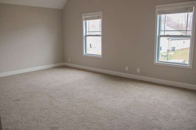 carpeted spare room featuring vaulted ceiling