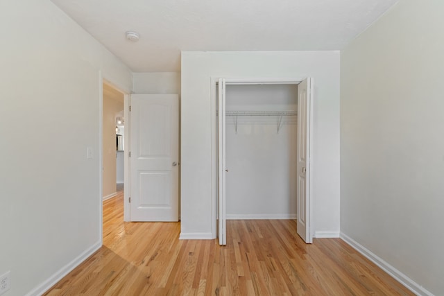 unfurnished bedroom with light hardwood / wood-style flooring and a closet