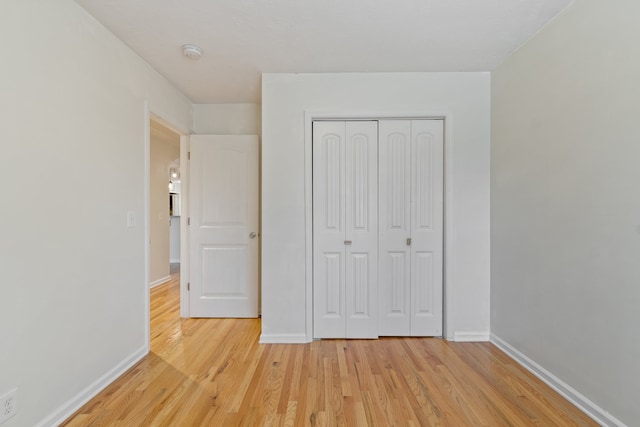 unfurnished bedroom with light wood-type flooring and a closet